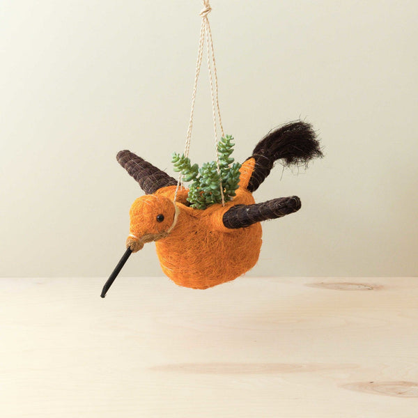 Hanging planter shaped like a bird with a small plant inside on a light background