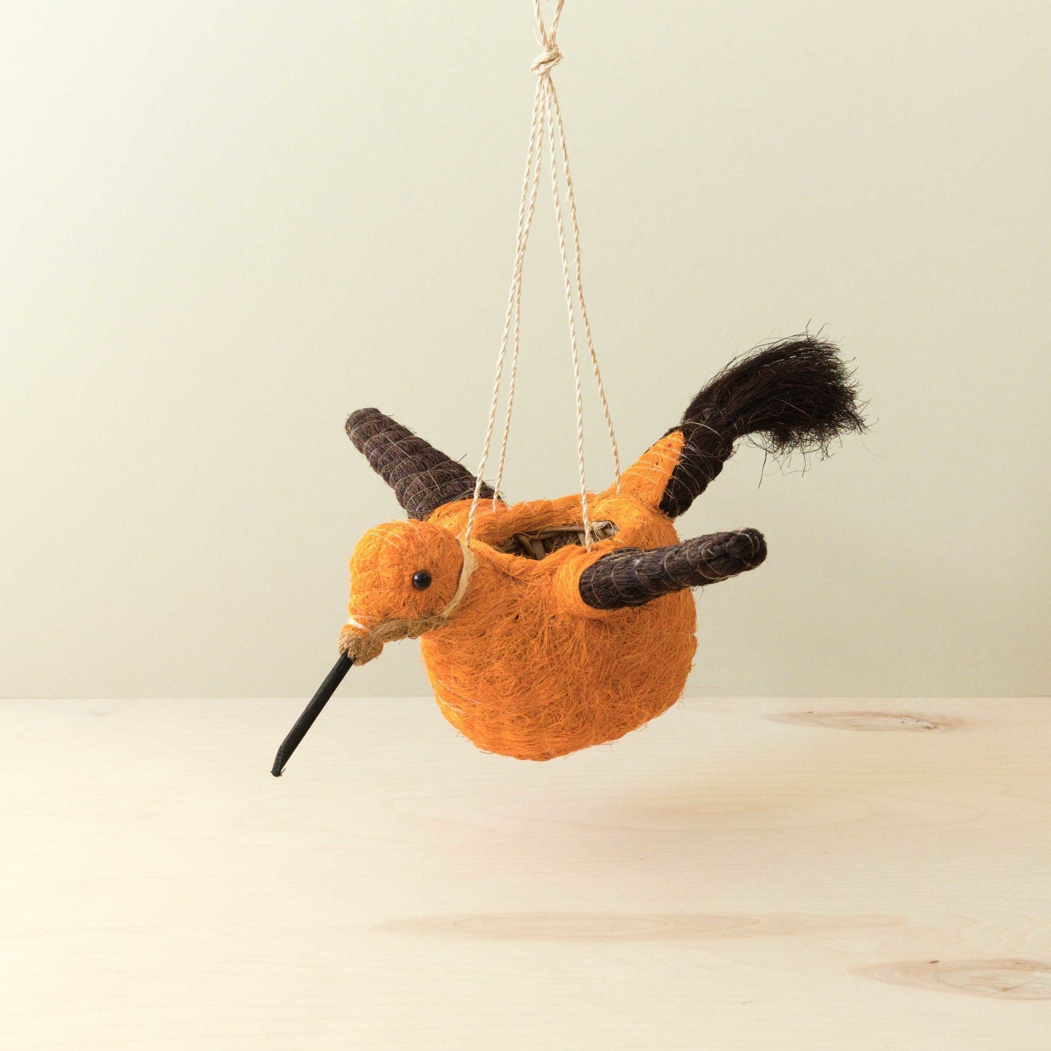 Plush toy bird hanging from a string on a light background