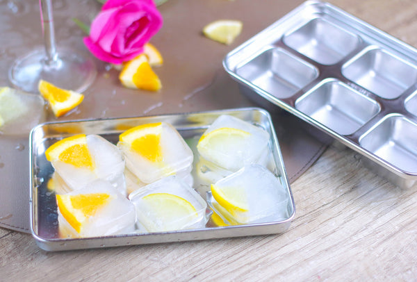 Metal baking tray with lemon slices and ice cubes on a wooden surface.