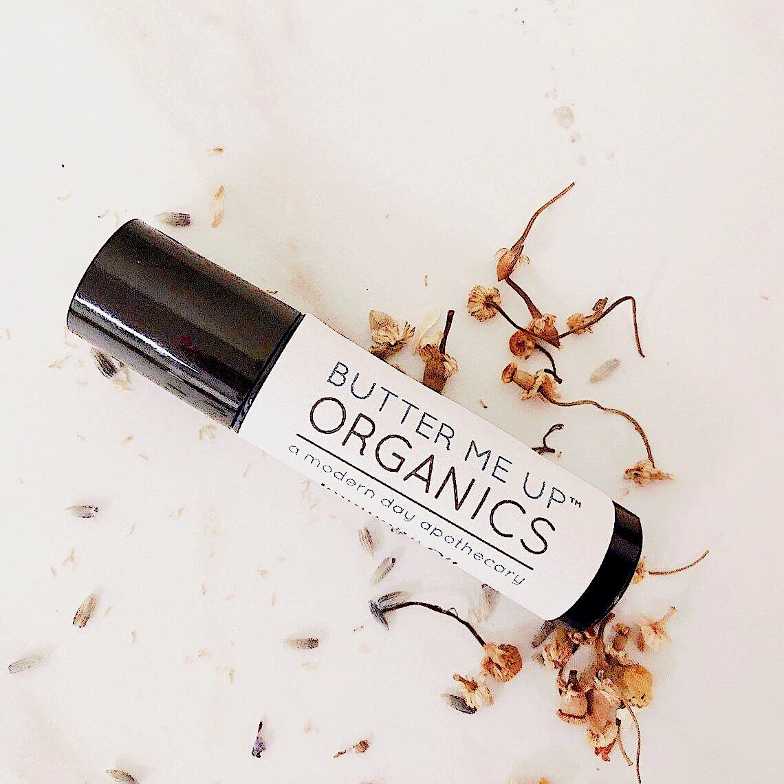 Butter Me Up Organics roll-on product on a light background with dried flowers.