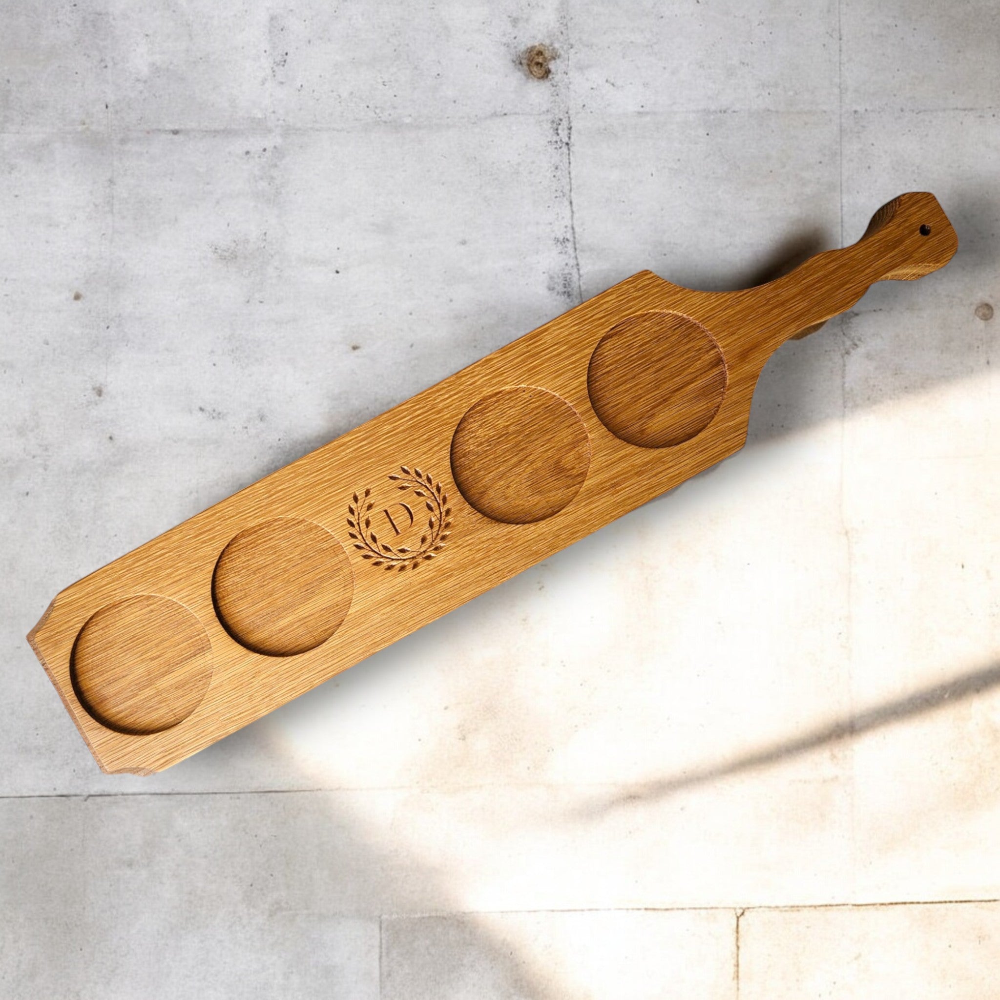Wooden drink tasting paddle with four round depressions on a light gray surface