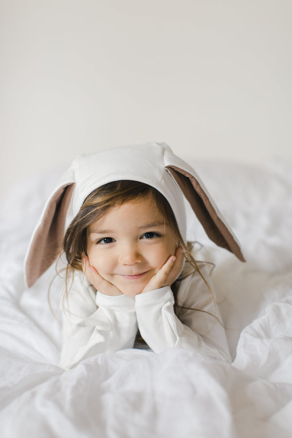 Child wearing bunny ears lying on a white blanket