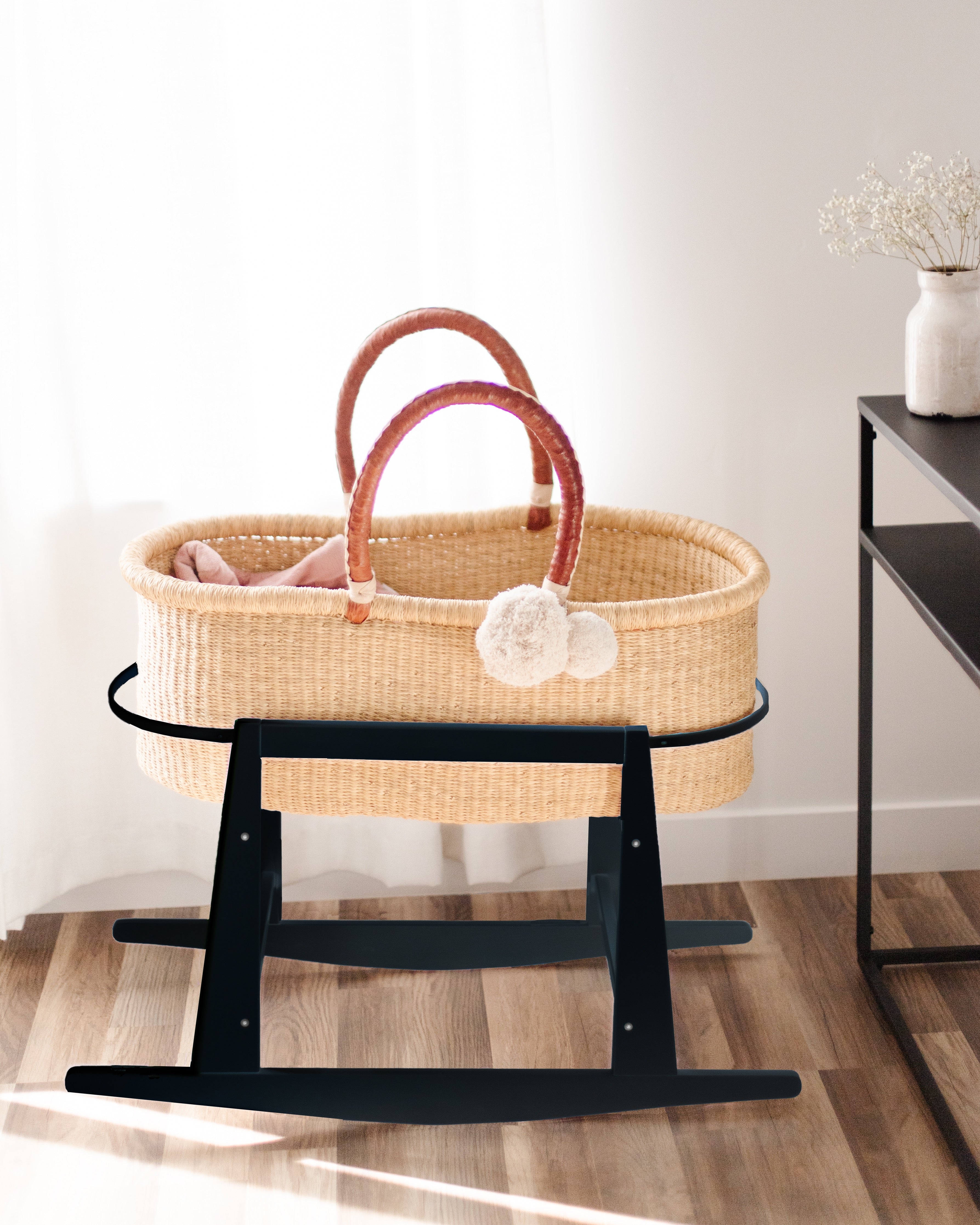 Close-up of the brake mechanism on the Plum+Sparrow black Moses basket stand showing lock and rock positions
