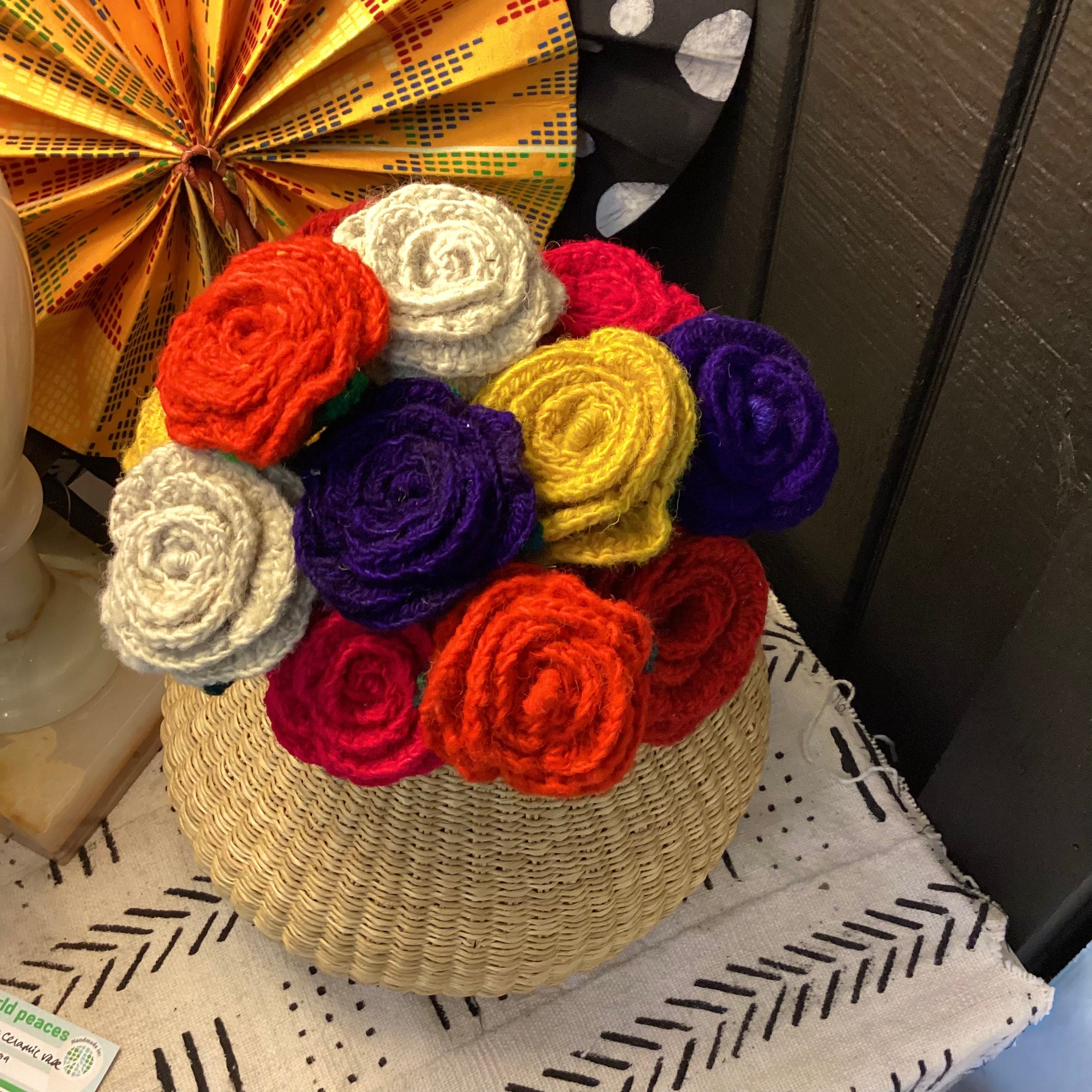 Woven basket with colorful crocheted flowers on a textured surface