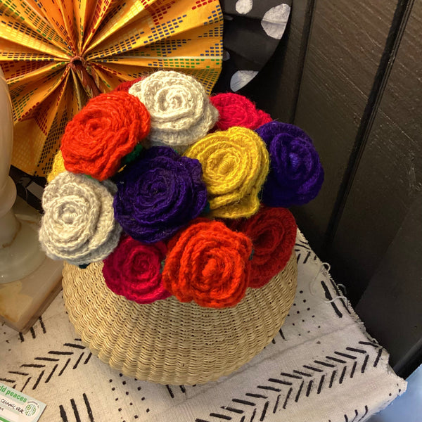 Woven basket with colorful crocheted flowers on a textured surface