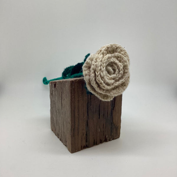 Wooden block with a knitted flower on a white background