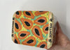 Container with papaya pattern and 'Don't Eat' label held by a hand on a white background