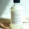 Butter Me Up Organics makeup remover bottle on a white surface with a wooden spoon and towel in the background.