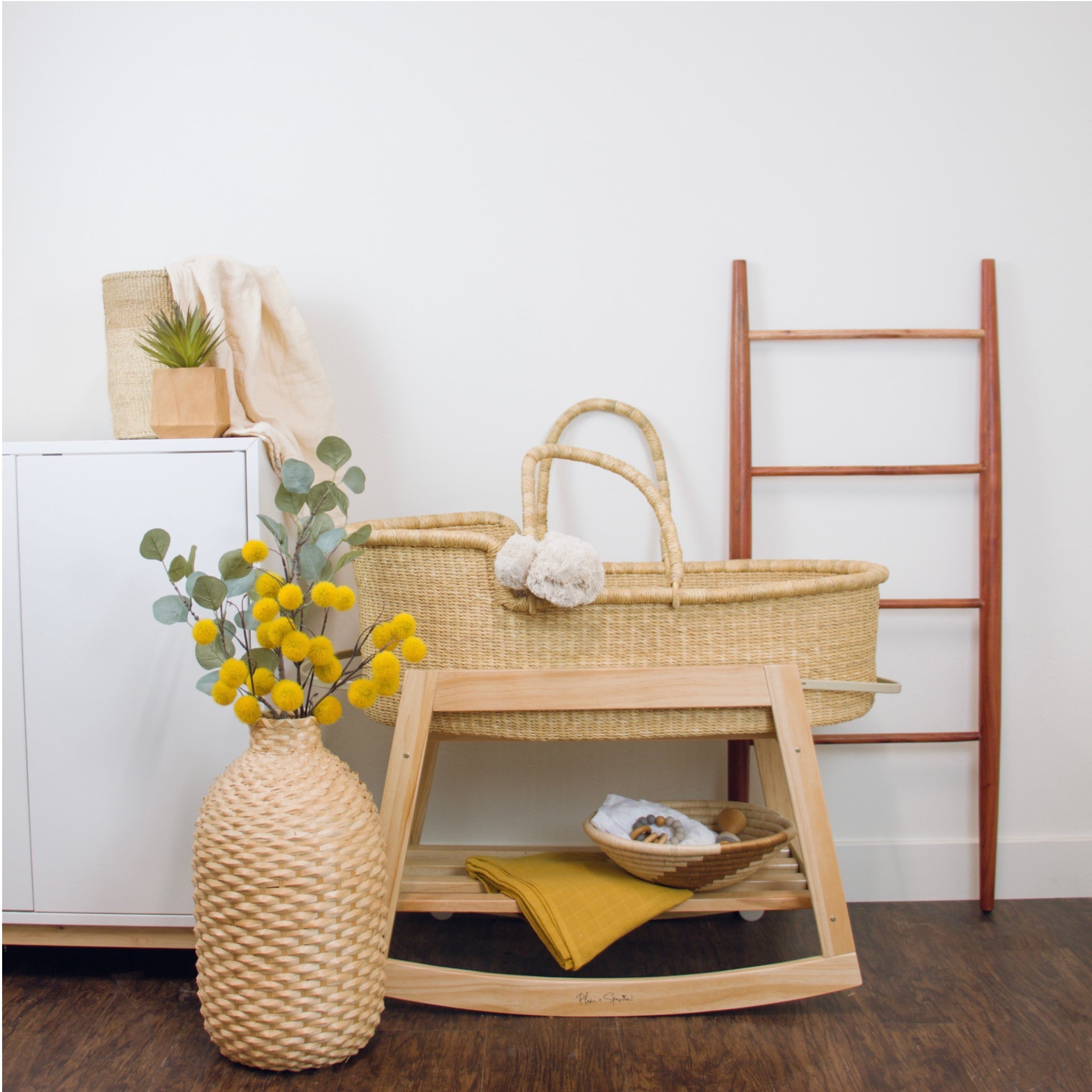 Close-up of the rocking brake mechanism on the Plum+Sparrow natural pine Moses basket stand