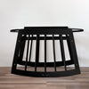 Black metal baby crib on a wooden floor with a white wall background