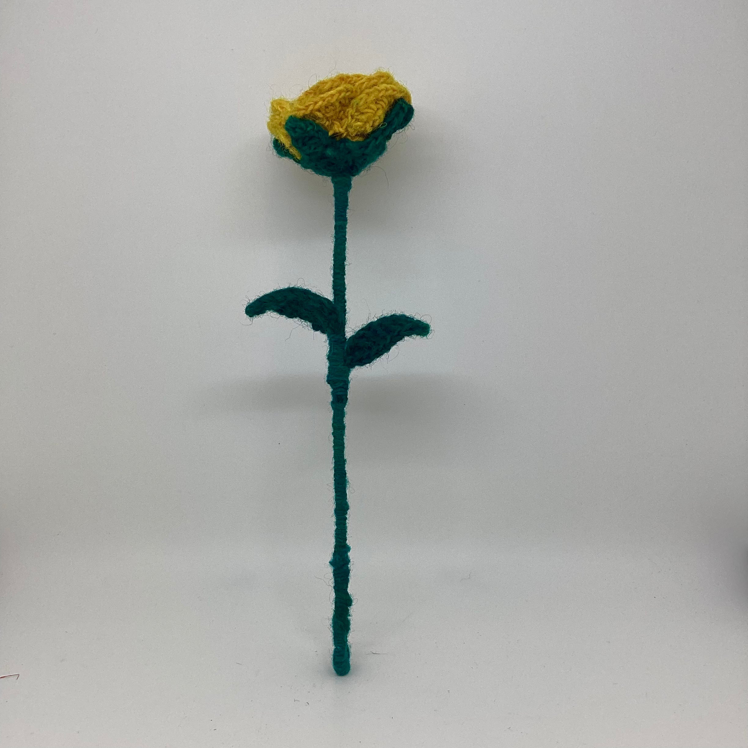 Knitted green flower with a yellow center on a white background