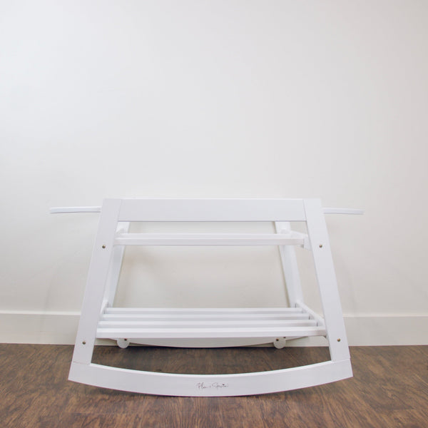 Close-up detail of the Plum+Sparrow rocking bassinet stand brake mechanism and adjustable straps in white