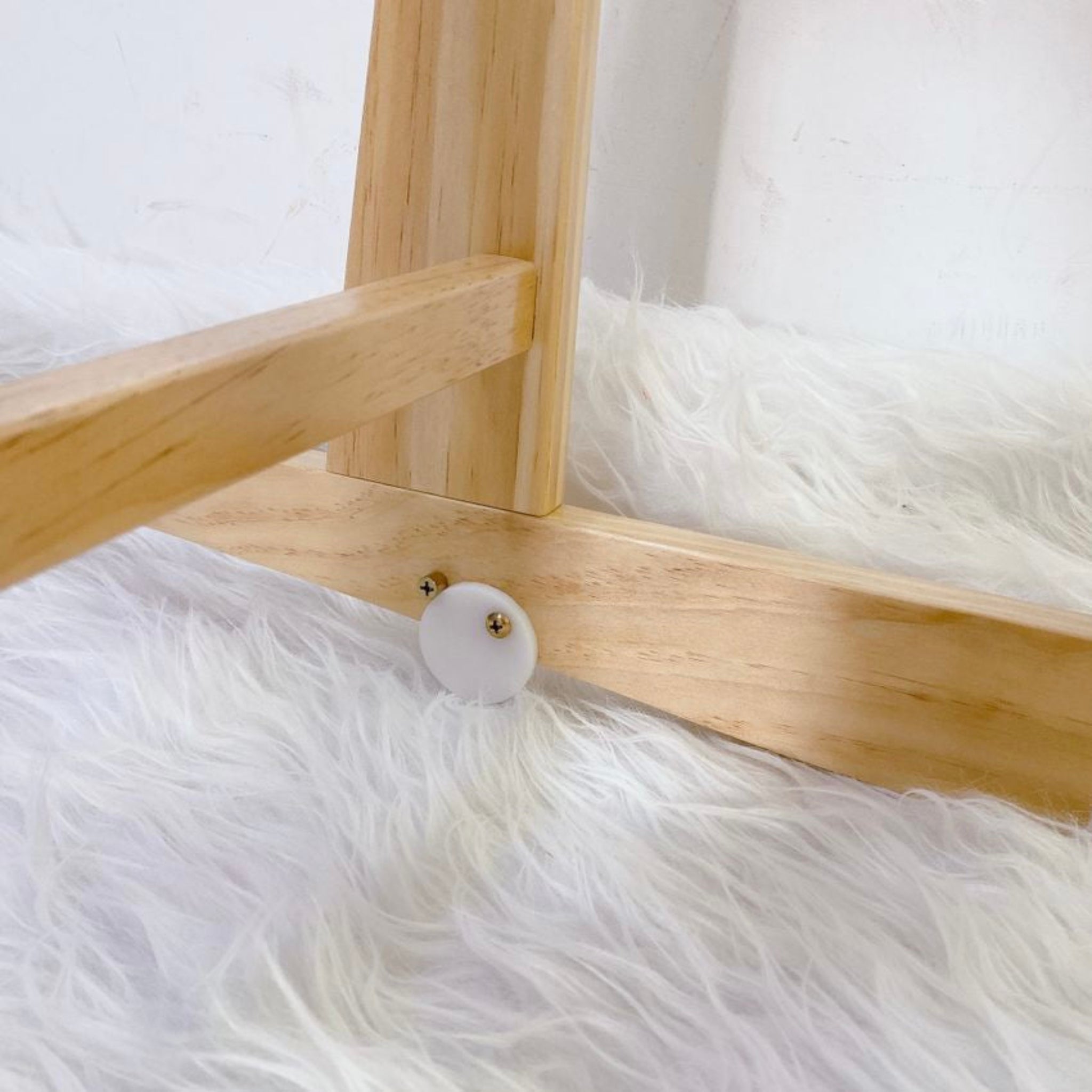 Wooden chair leg with white circular foot on a white fluffy surface