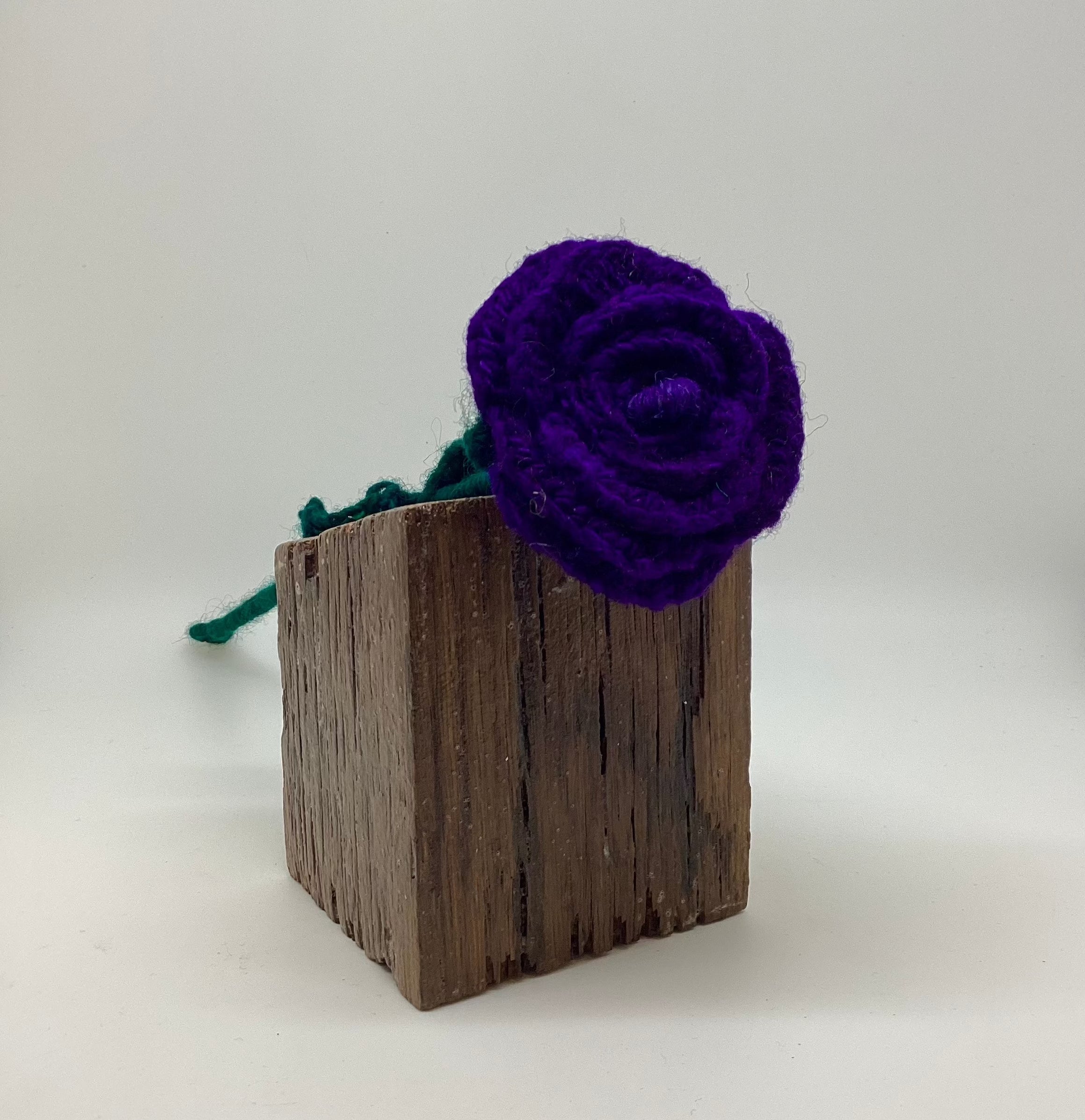 Purple flower on a wooden block against a white background