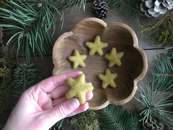 Close view of felted wool stars in Gold Clay Yellow showing their handmade shapes