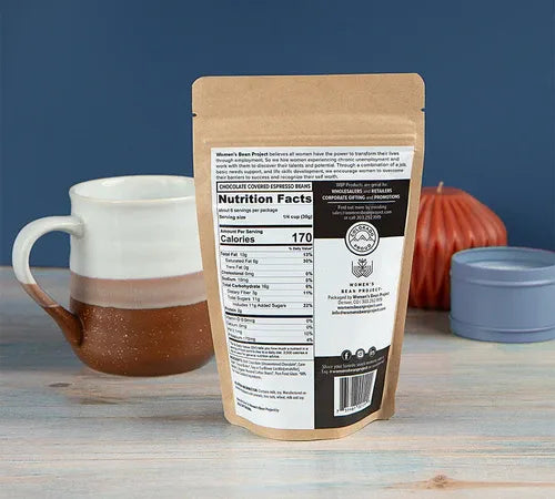 Kraft coffee package with nutrition label on a wooden surface with a mug and pumpkin in the background
