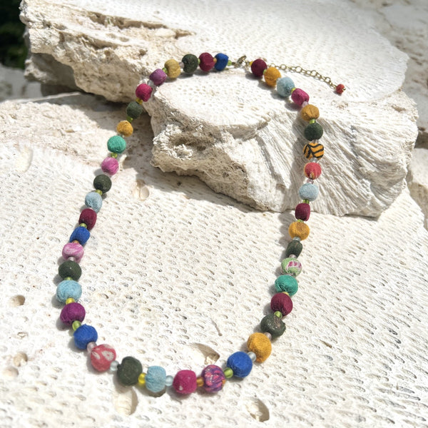 Colorful beaded necklace on a textured stone surface