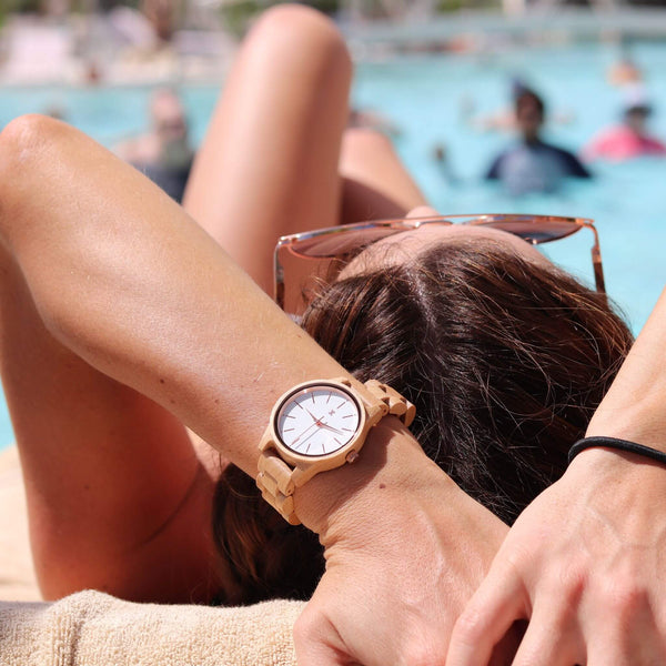Person relaxing by a pool wearing a wooden watch