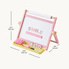 Pink and yellow wooden children's easel with a white writing board, pink gingham trim, a yellow tray with a brush, eraser, and markers, shown with dimension lines and text on a light beige background.