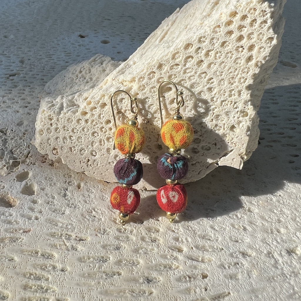 Colorful beaded earrings on a textured stone surface