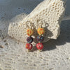 Colorful beaded earrings on a textured stone surface