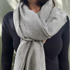 Person wearing a knitted gray cotton scarf against a neutral background