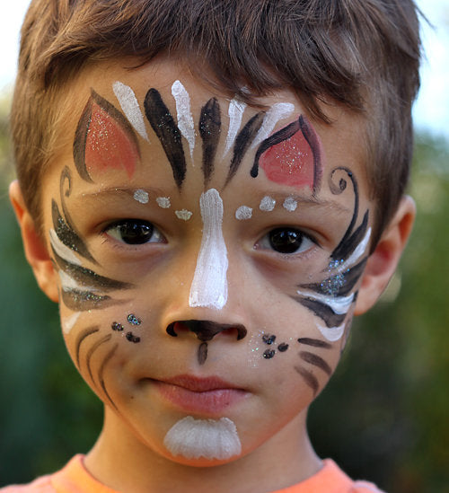 Child with tiger face paint against a blurred natural background