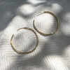 Gold hoop earrings on a textured white fabric background