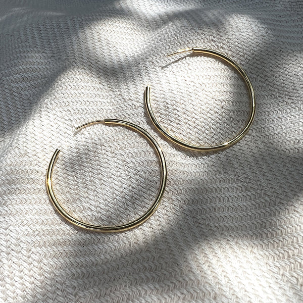 Gold hoop earrings on a textured white fabric background
