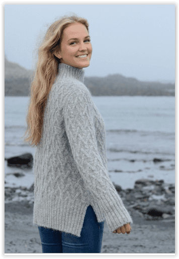 Woman wearing a gray knitted sweater by a body of water