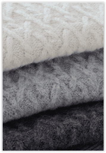 Stack of knitted fabric in white, gray, and black.