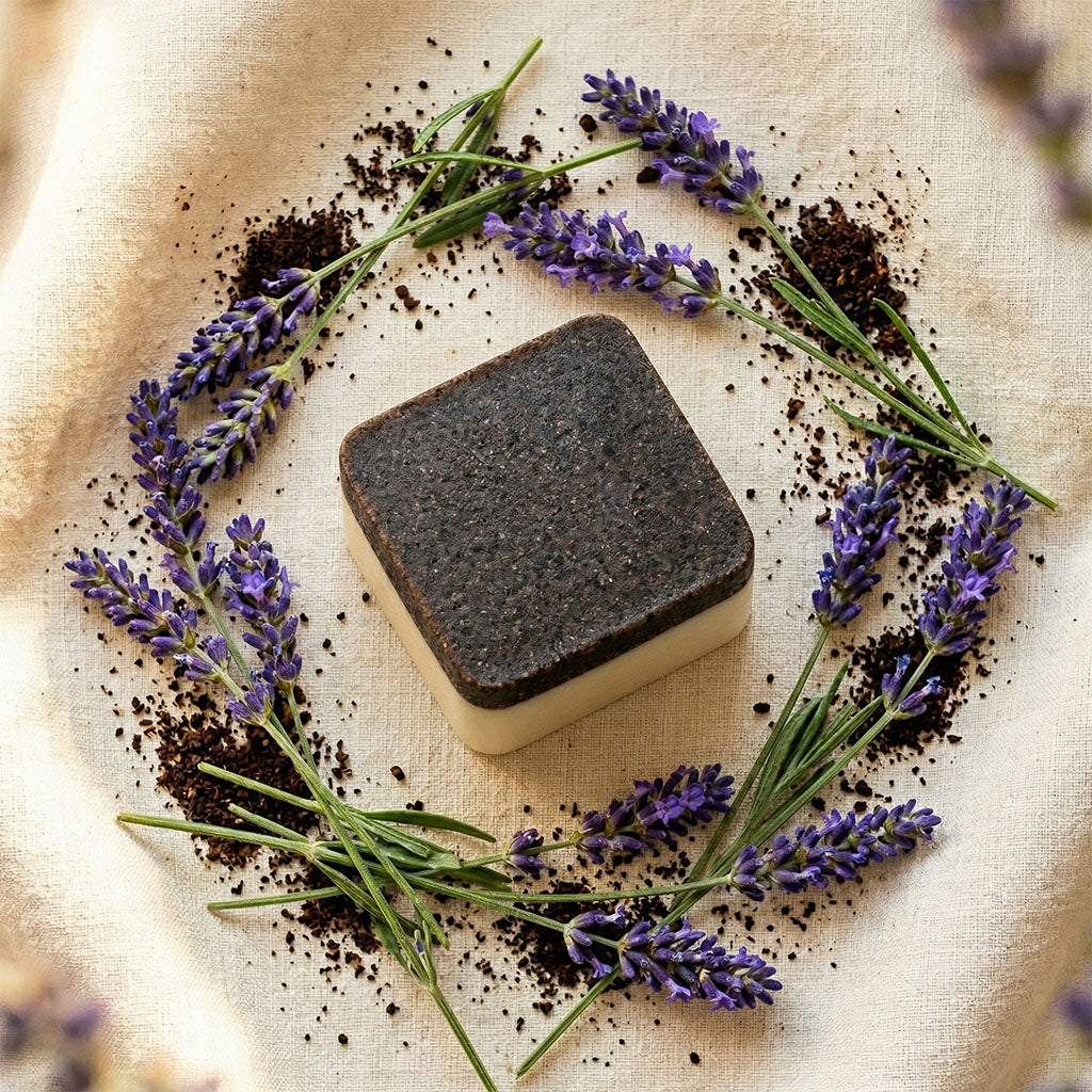 Square bar of soap with lavender and coffee grounds on a beige fabric background