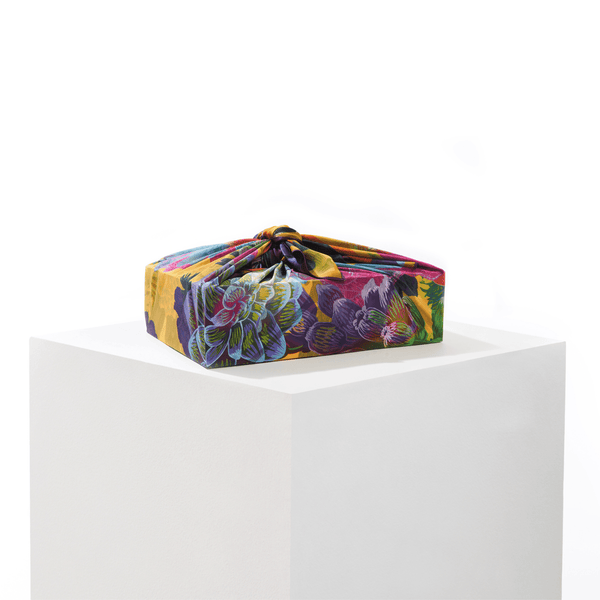 Lilac silk furoshiki wrap tied around a gift, displaying summer floral pattern in lilac and complementary tones