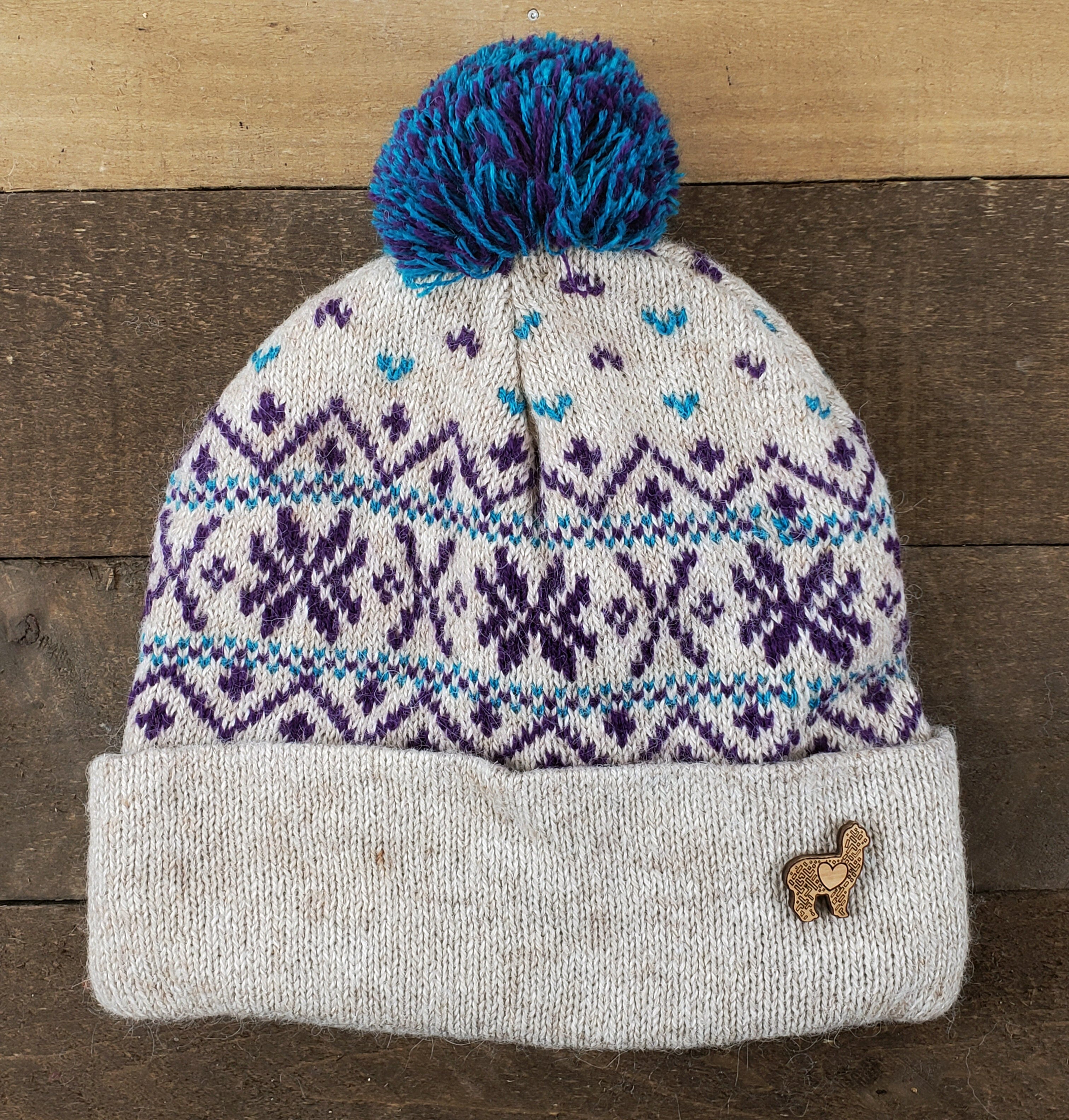 Knitted beanie with a blue pom-pom on a wooden surface