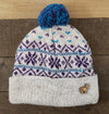 Knitted beanie with a blue pom-pom on a wooden surface