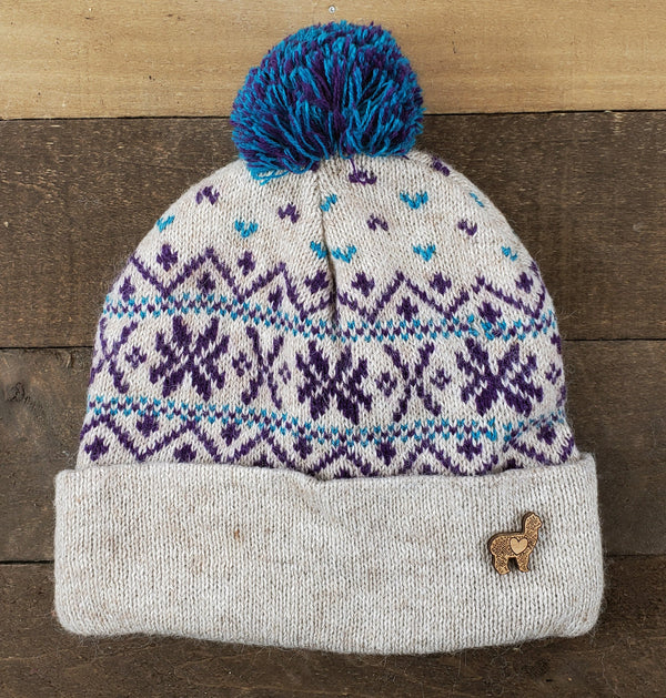 Knitted beanie with a blue pom-pom on a wooden surface