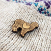 Wooden brooch with heart design on a textured fabric background