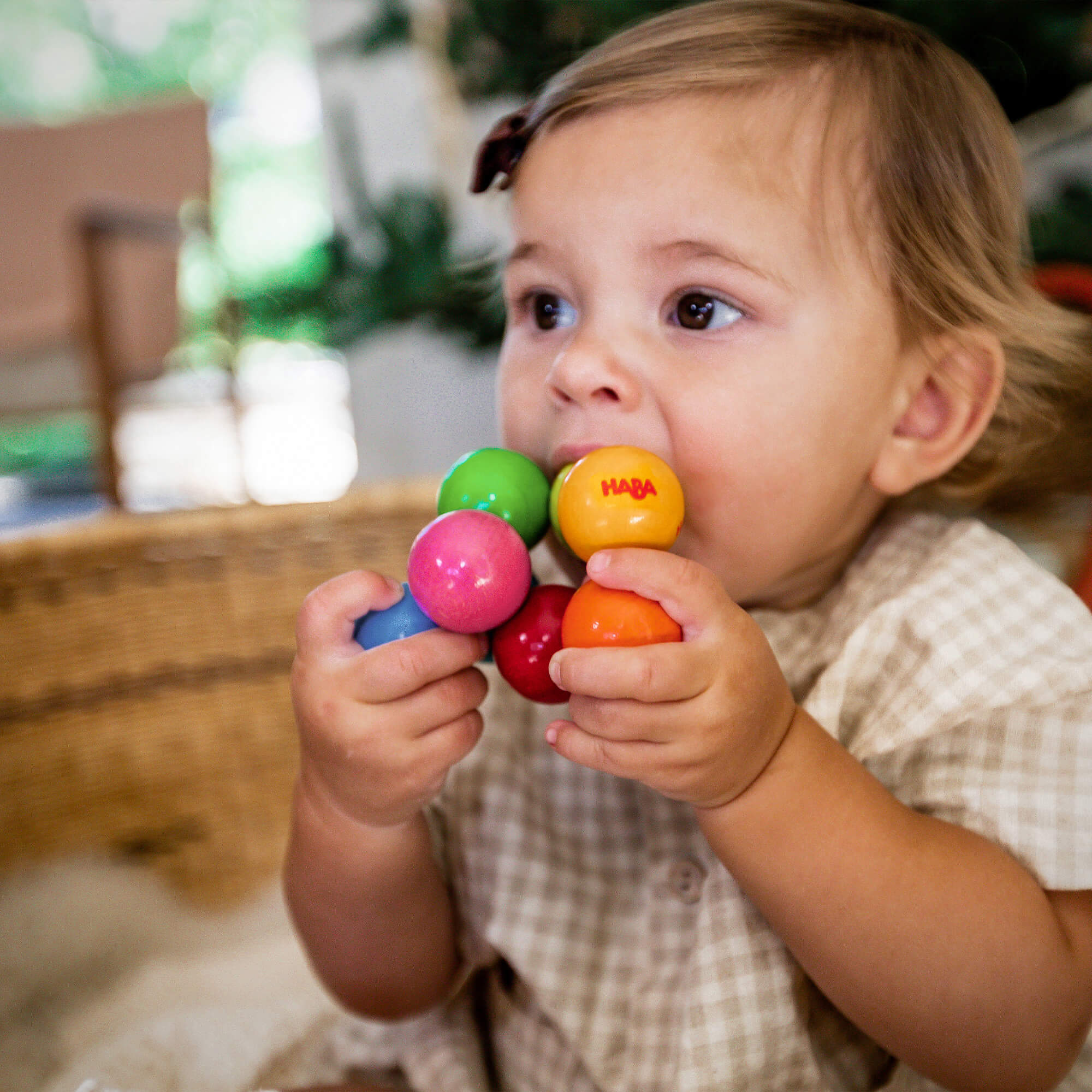 Baby playing with HABA Magica wooden teething toy with smooth colorful beads