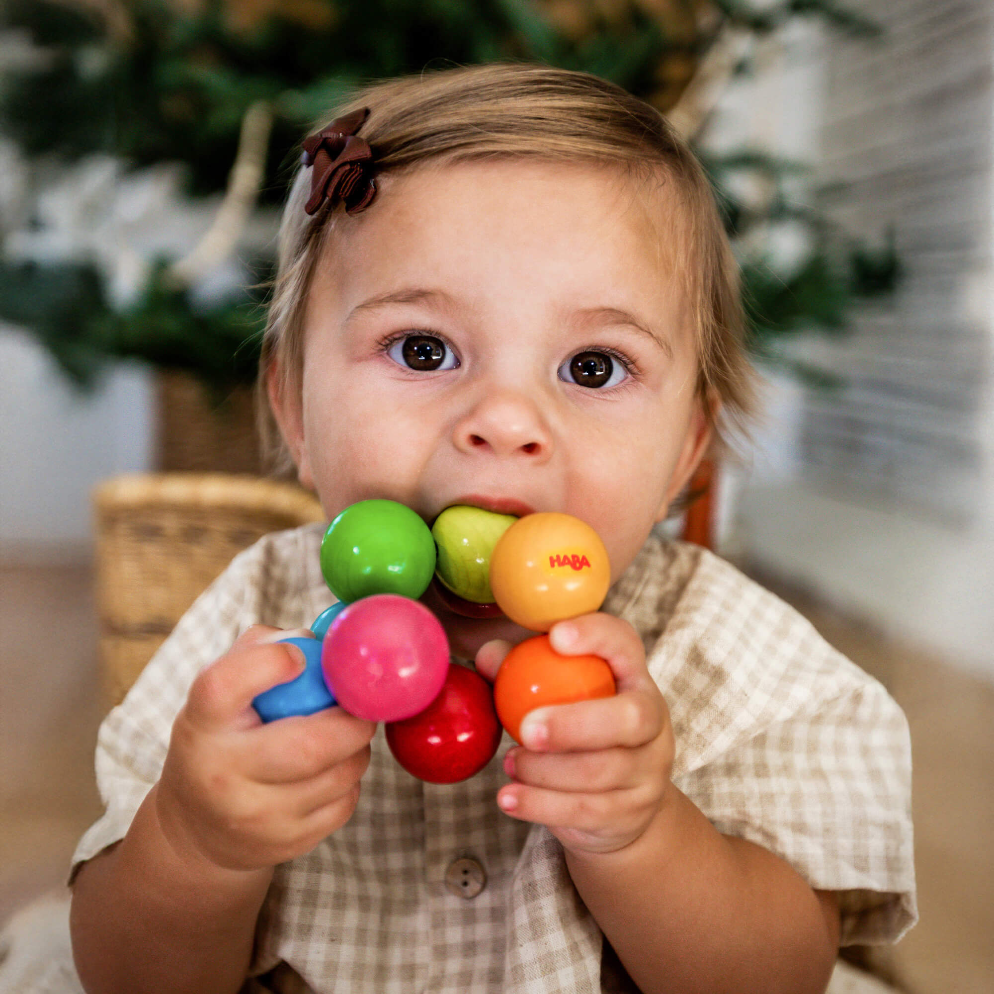 Close-up of HABA Magica wooden baby toy showing brightly colored beads threaded on elastic