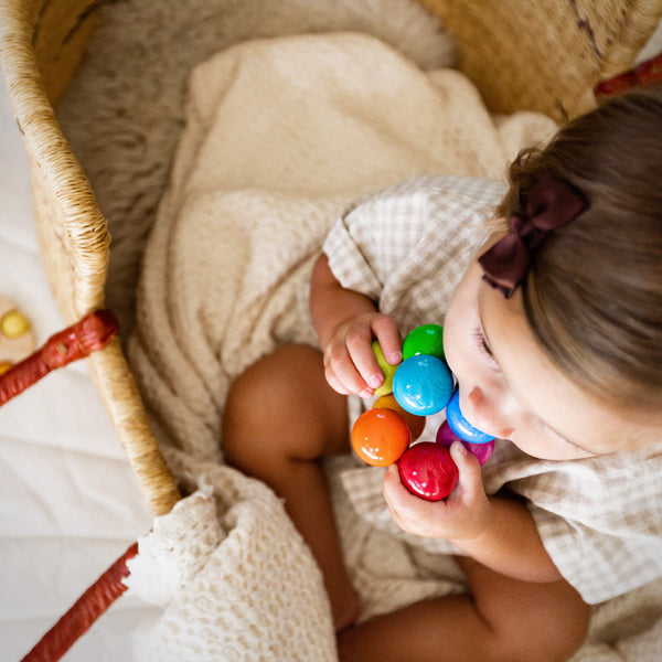 HABA Magica wooden grasping toy held in baby's hand during sensory play
