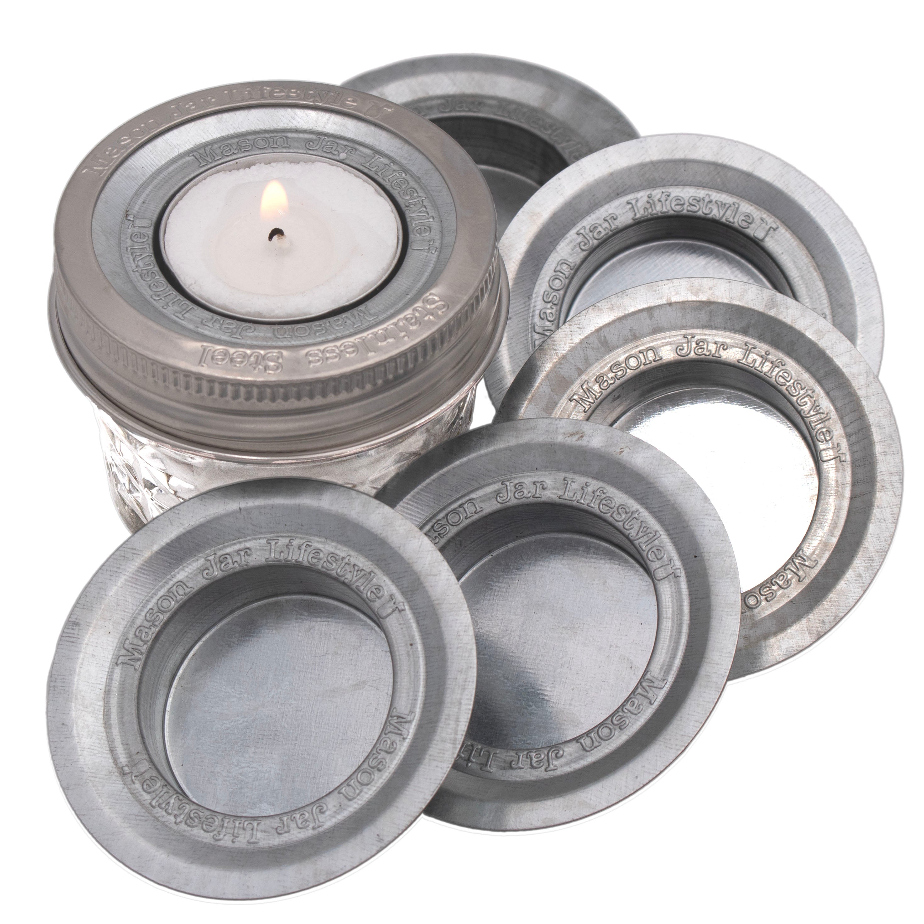 Set of Mason jar lids with a lit candle inside one of them on a white background