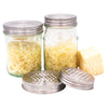 Two glass jars with metal lids containing shredded cheese on a white background