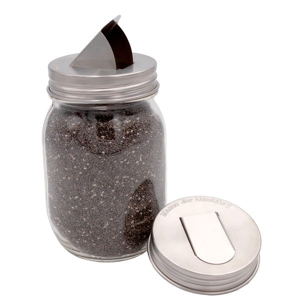 Clear jar with black pepper and silver lid on a white background