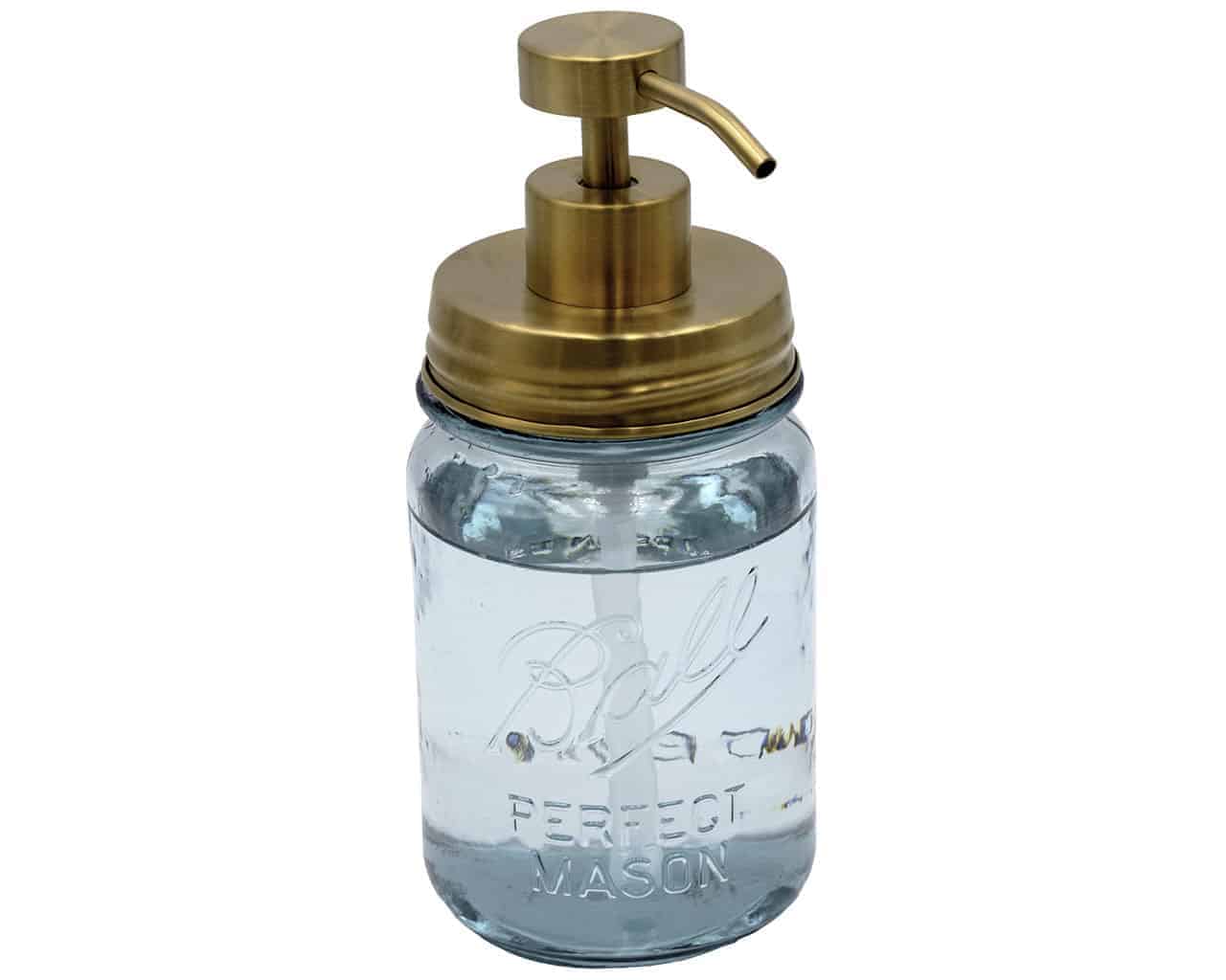 Clear glass mason jar with gold pump lid on a white background