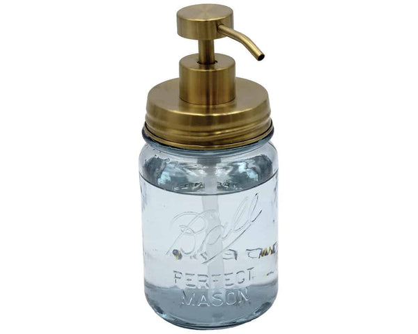 Clear glass mason jar with gold pump lid on a white background