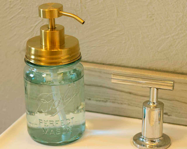 Glass mason jar with gold pump top on a bathroom counter