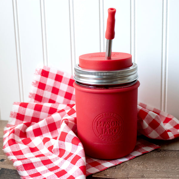 Red mason jar with a straw lid on a red and white checkered cloth