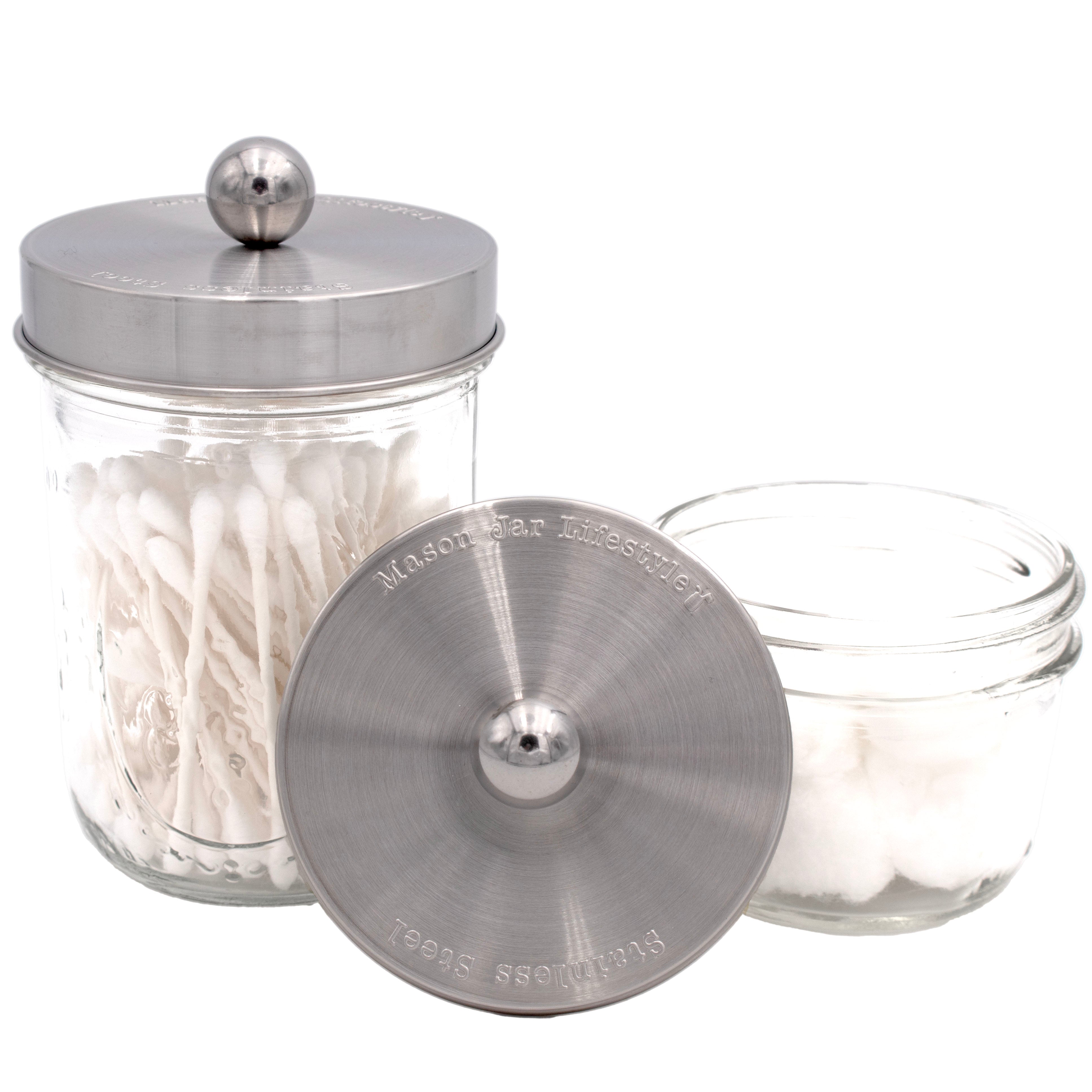 Glass jar with silver lid containing cotton swabs on a white background