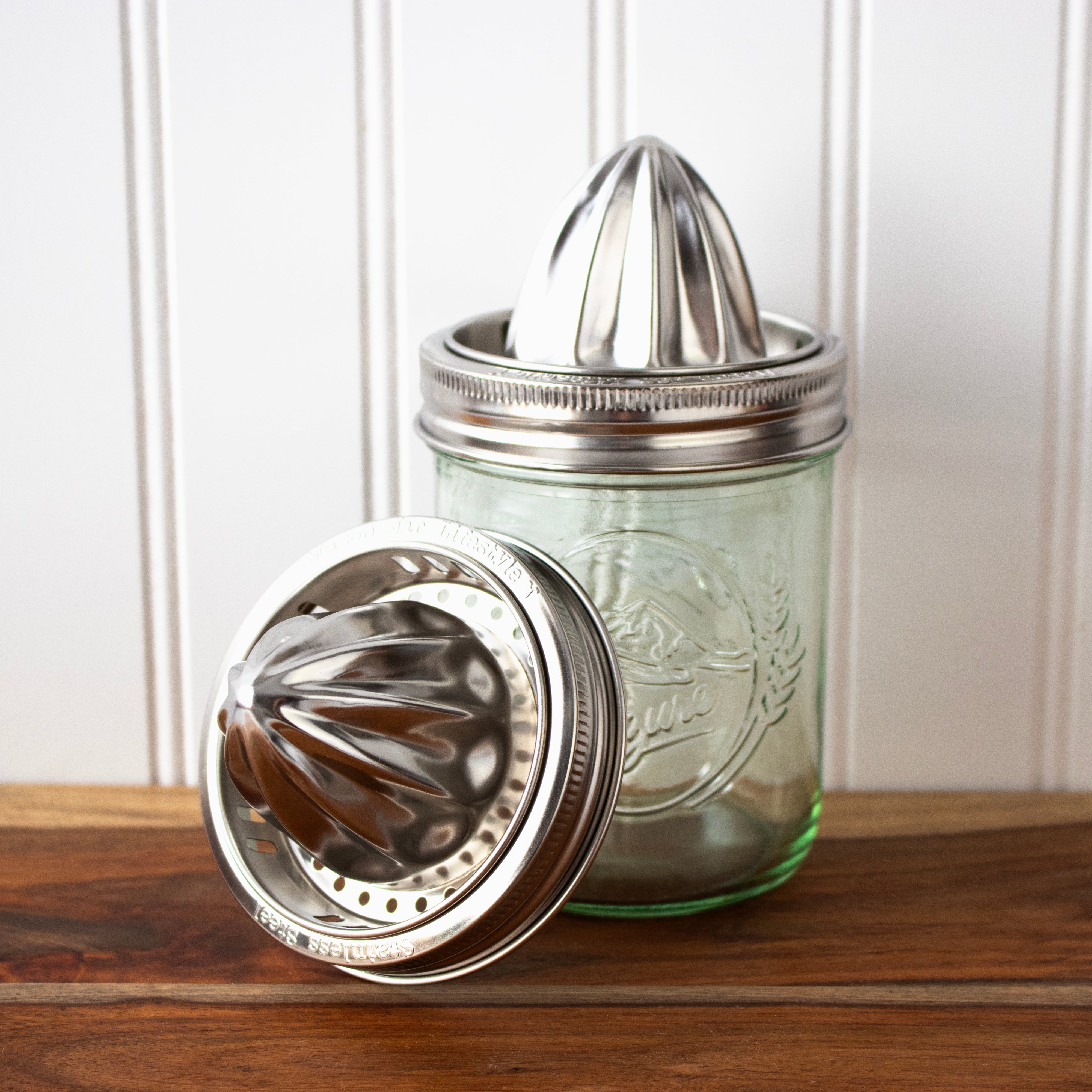 Mason jar with metal juicer attachment on a wooden surface