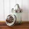 Mason jar with metal juicer attachment on a wooden surface